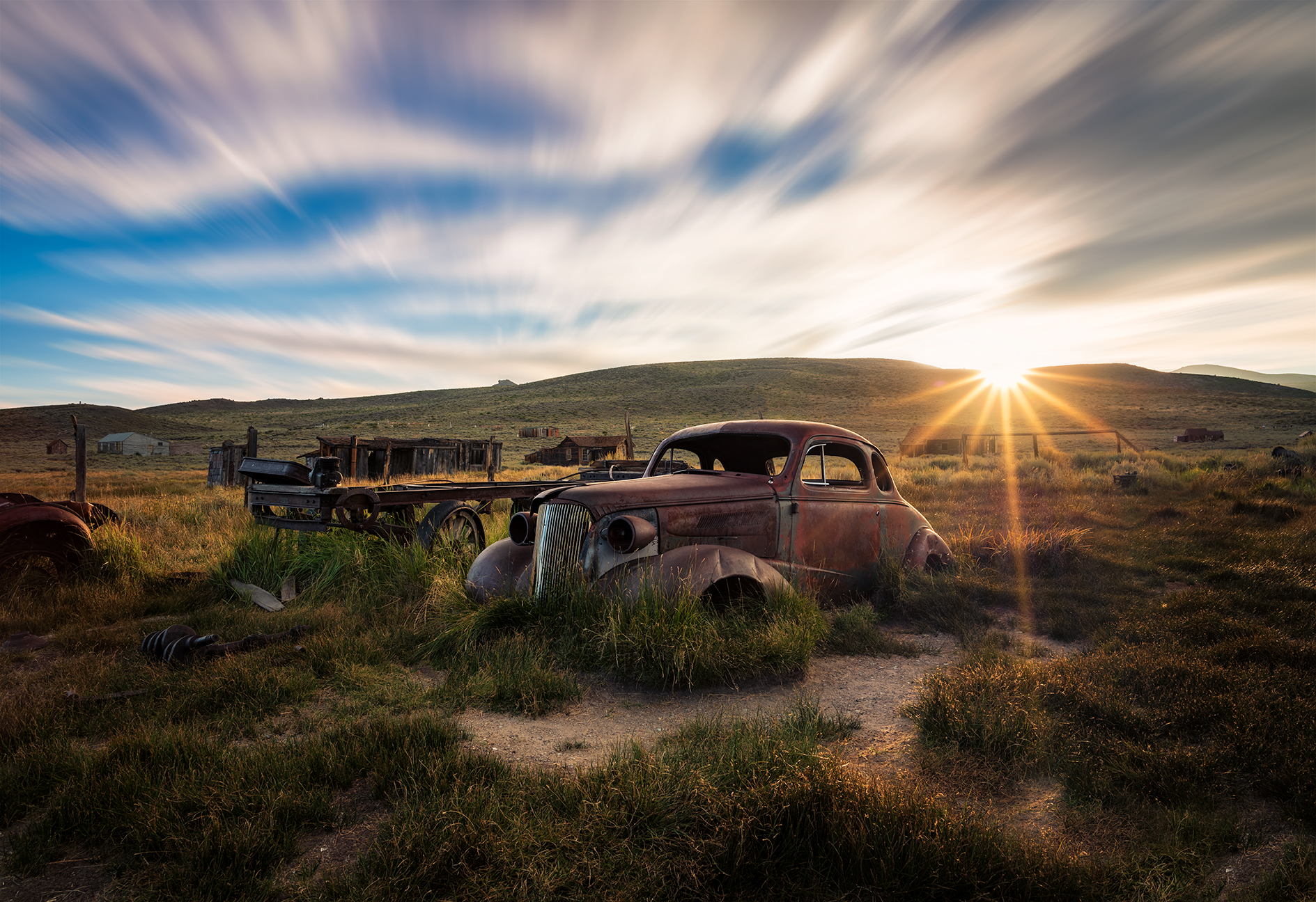 Abandoned car in the California hills at sunset