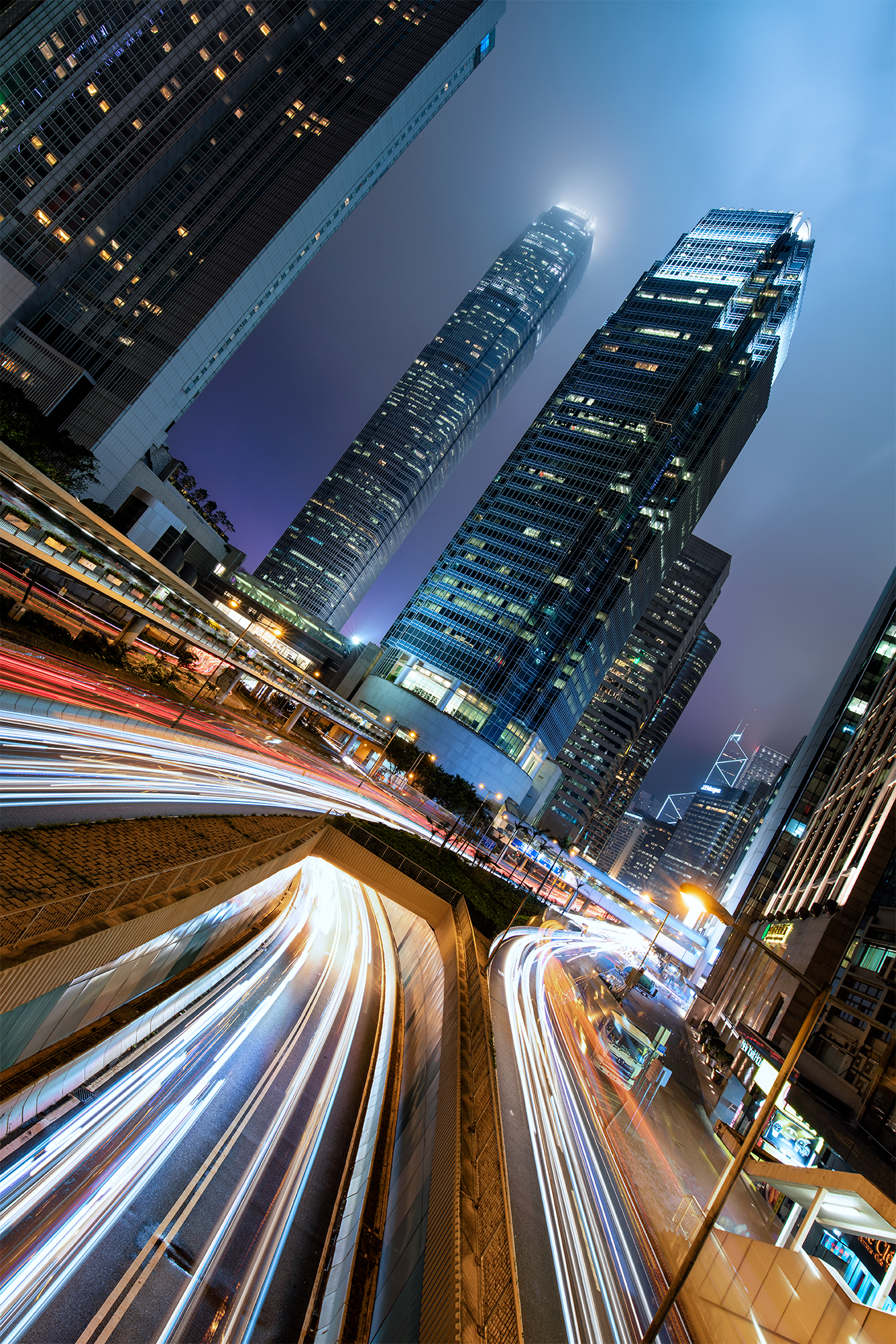 light trails of traffic cruising through downtown central Hong Kong at night in front of the IFC building
