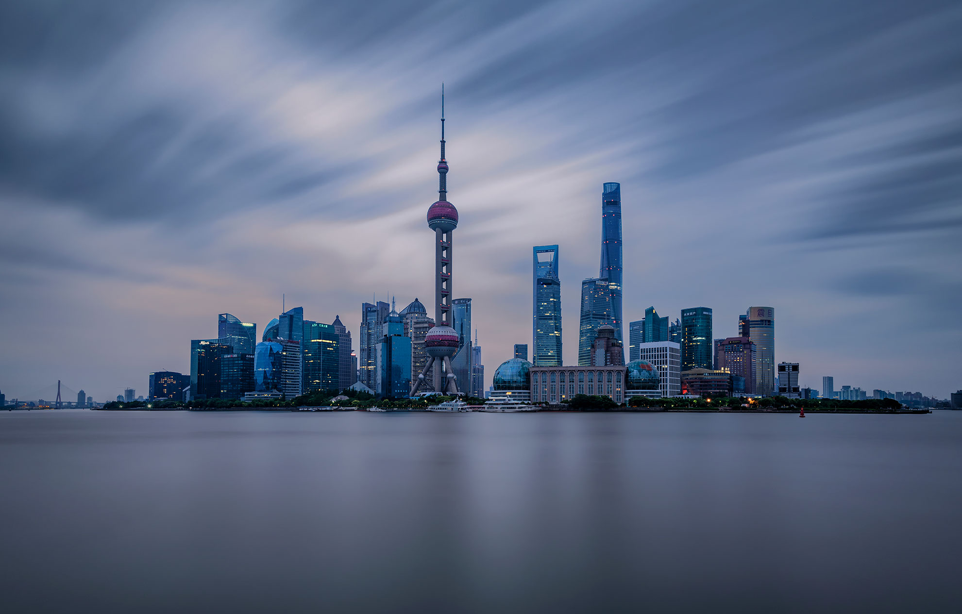 lights of Shanghai's Puxi downtown skyscrapers reflect over the water from the view of the Bund